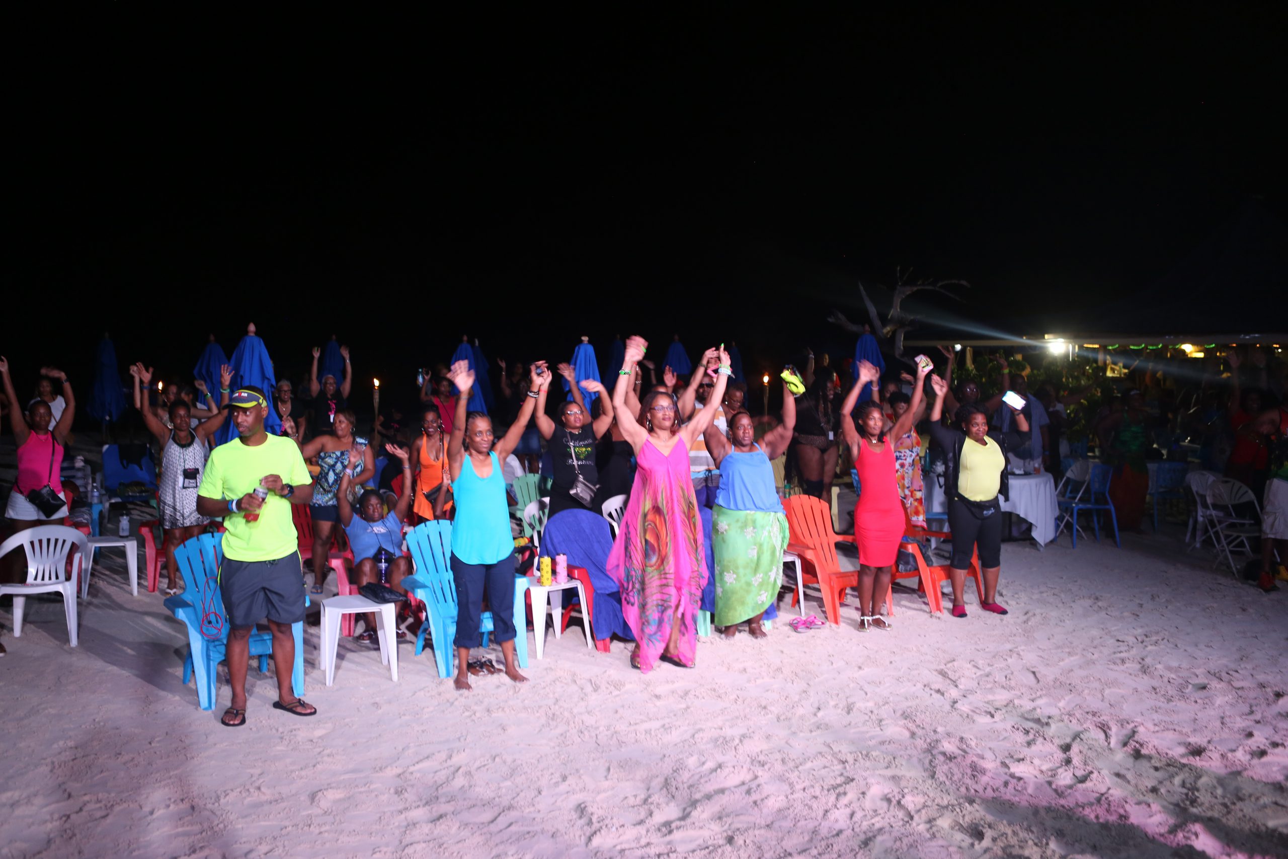 A group of people standing on top of a sandy beach.