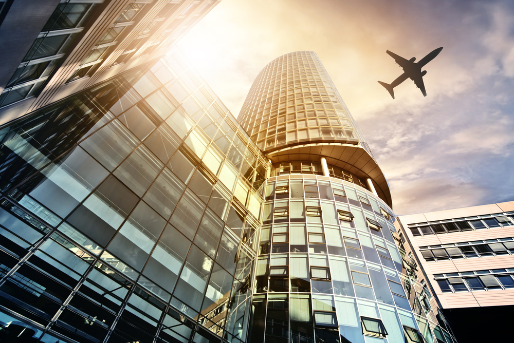 A large building with a plane flying over it.