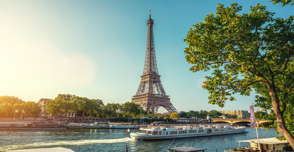 A boat is traveling down the river near the eiffel tower.