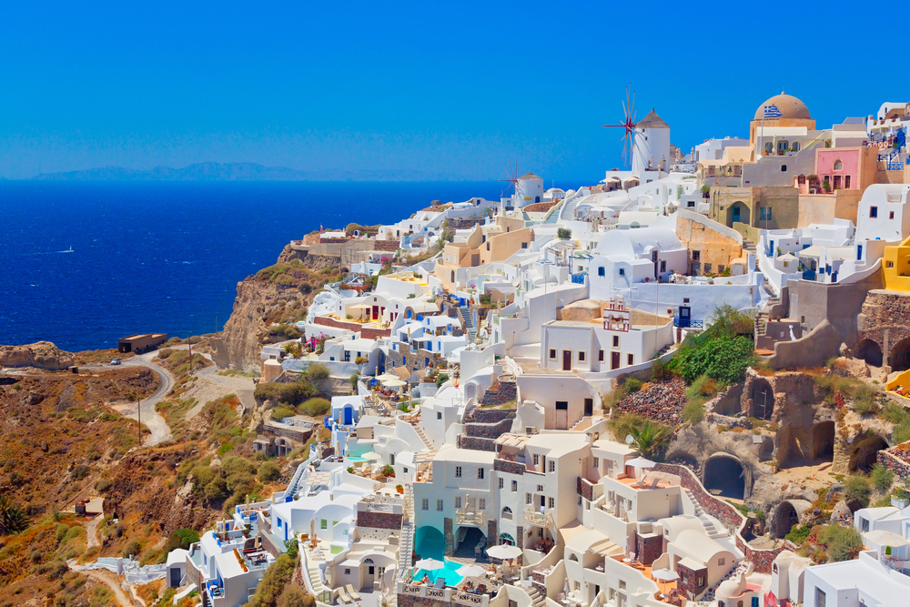 A view of the ocean and buildings on top of a hill.