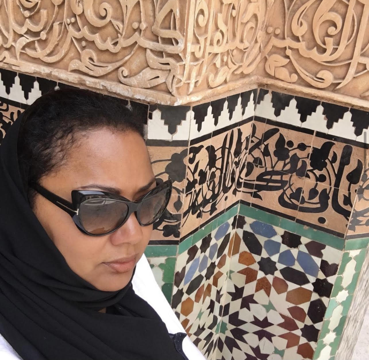A woman wearing sunglasses and a black headscarf.