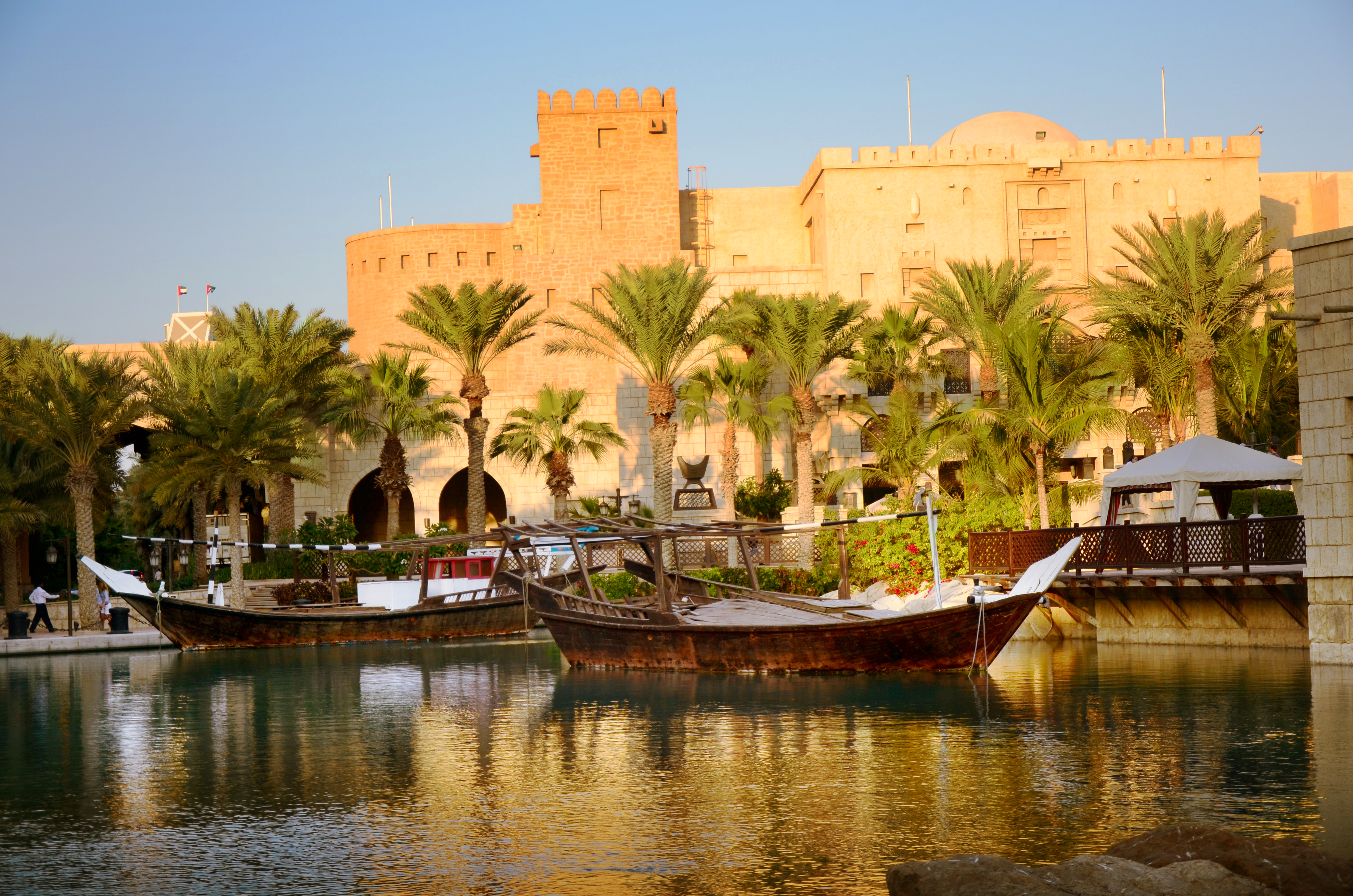 A group of boats in the water near palm trees.
