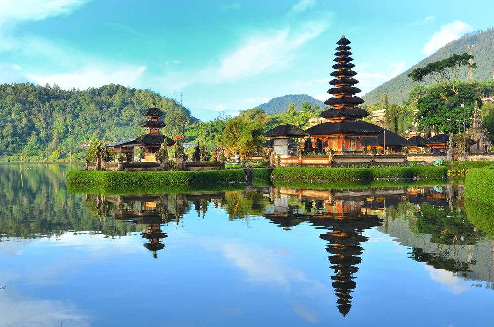 A lake with mountains in the background and a temple on top of it.