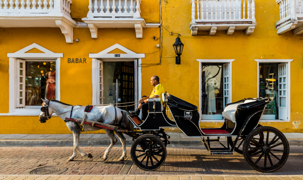 A man riding in a carriage pulled by two horses.