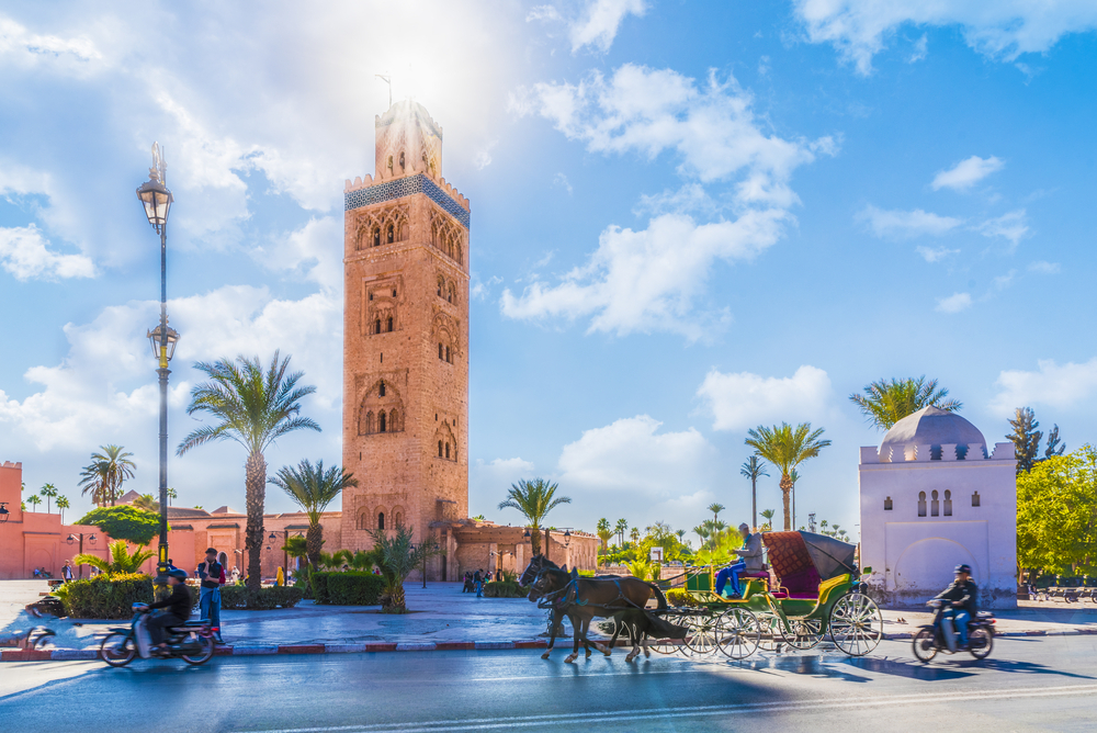 A horse drawn carriage rides past a large tower.