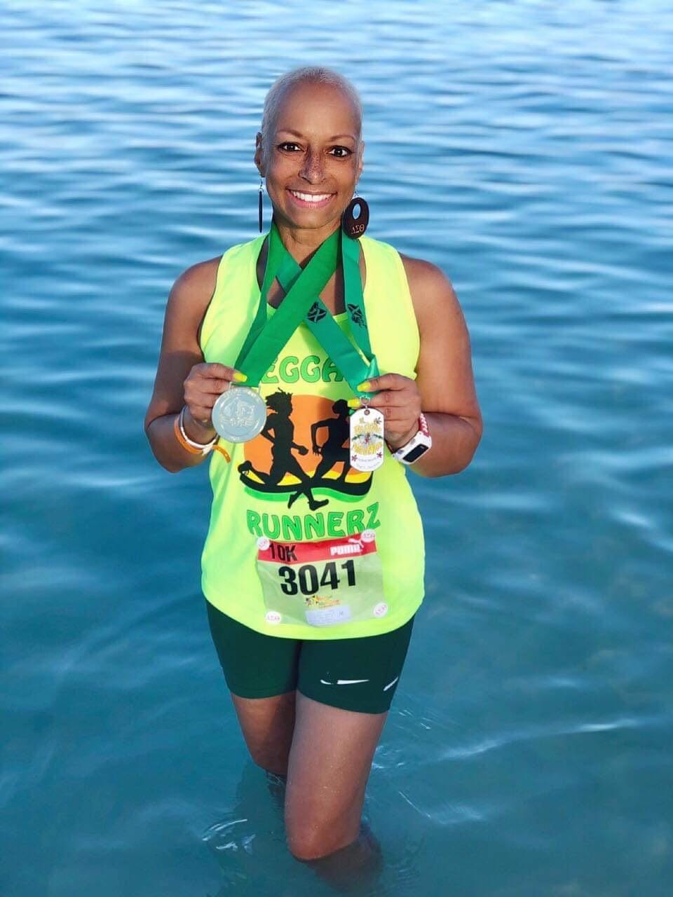 A woman holding up her medal in the water.
